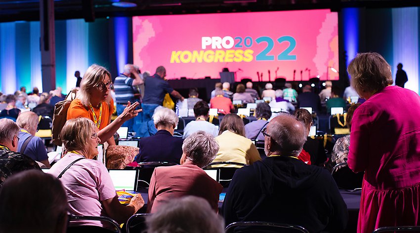 En stor sal med människor, i bakgrunden en scen med en vepa med texten "PRO:s kongress 2022"