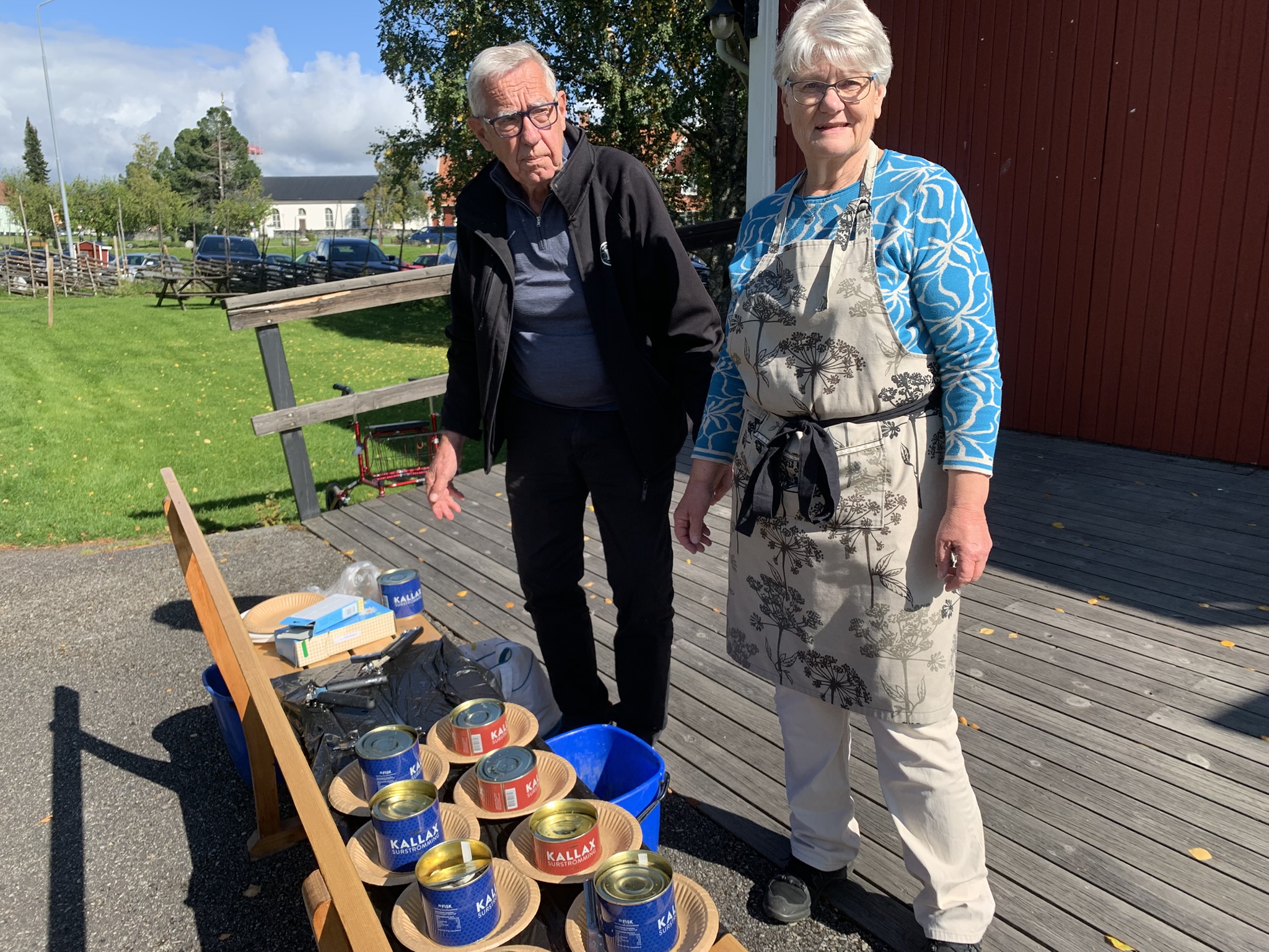 En kvinna och en man som öppnar surströmmingsburkar