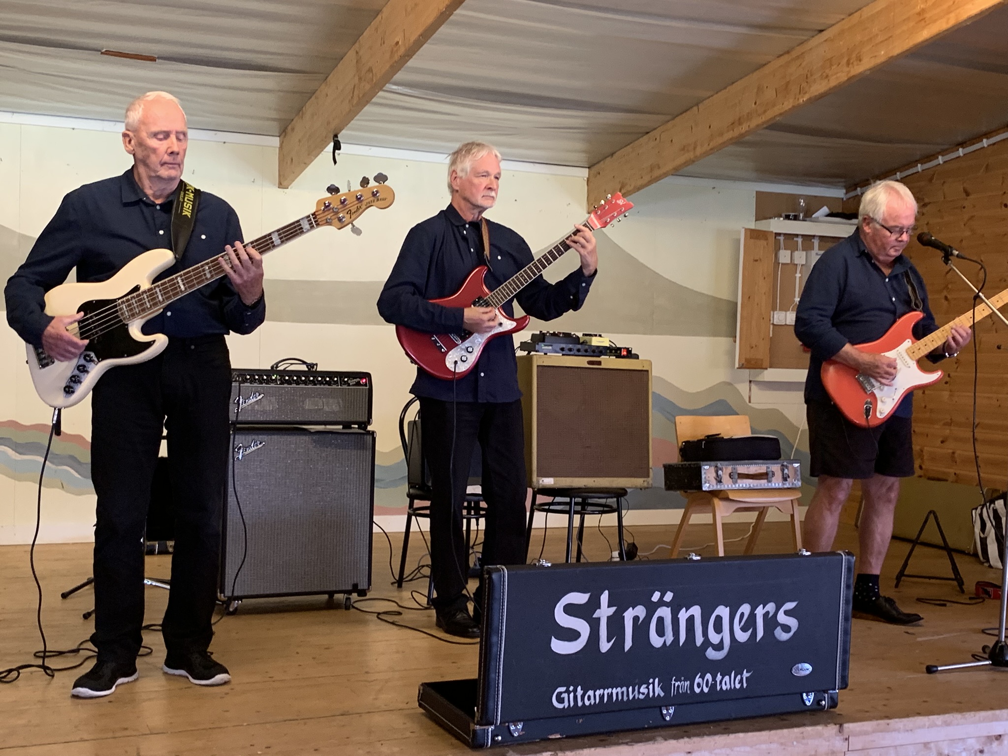 Tre män som spelar gitarrer.