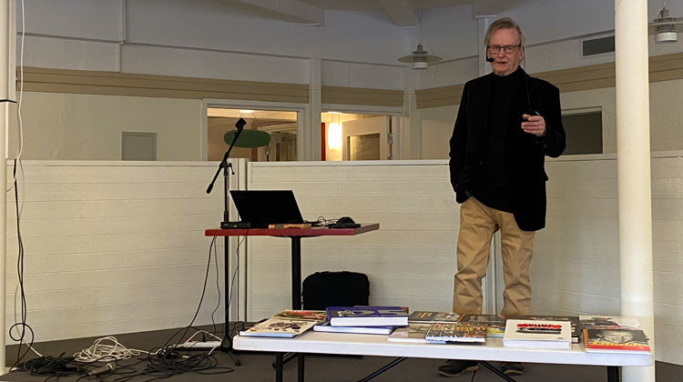 Ulf "Krigarn" Kriström berättade om sitt författarskap när PRO Valbo hade årets första träff. Det har under åren blivit så många titlar att böckerna fyller en Ikea-kasse till bredden. Foto: Ulf Lindman
