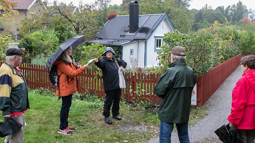 Vid entrén till Dalens koloniförening. Christina Tillö berättar under PRO Kärrtorps vandring.