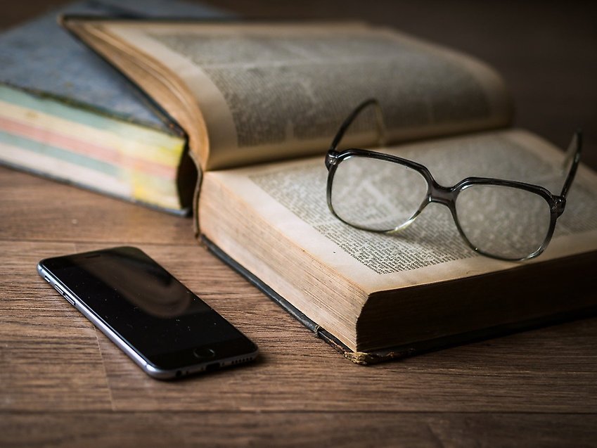 Glasögon och mobil vid bok