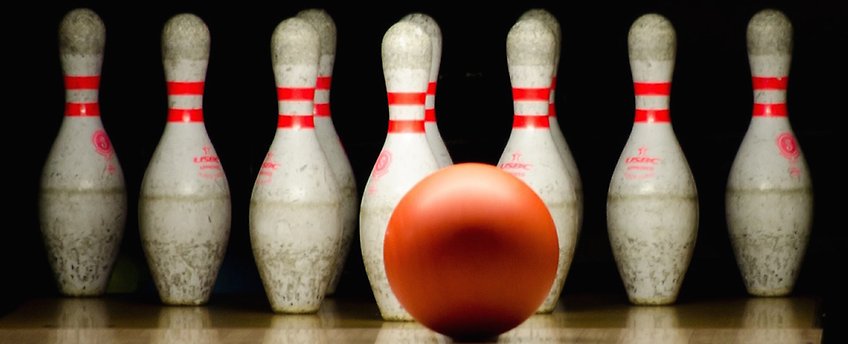En rad bowlingkäglor med ett klot framför