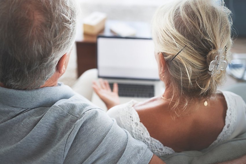 Två pensionärer sitter i en soffa framför en dator