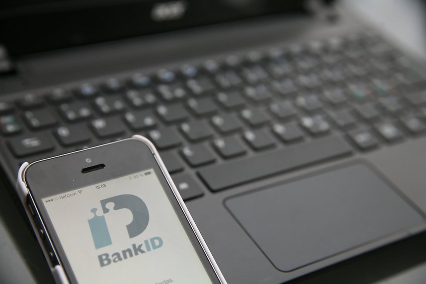 Svart dator med mobil framför vars skärm visar bankids logotyp