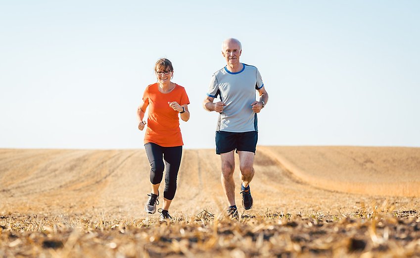 En man och kvinna joggar sida vid sida över ett fält.