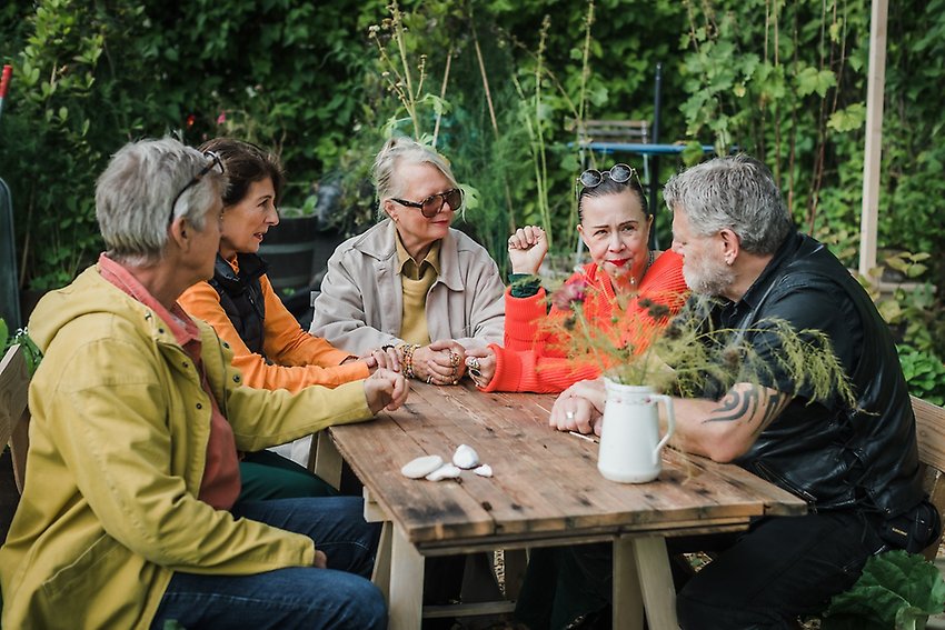 Människor samtalar runt ett bord sommar foto Anneli Nygårds