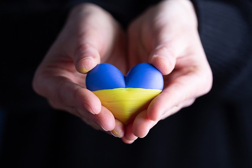 två händer håller i ett hjärta som har färgerna av Ukrainas flagga